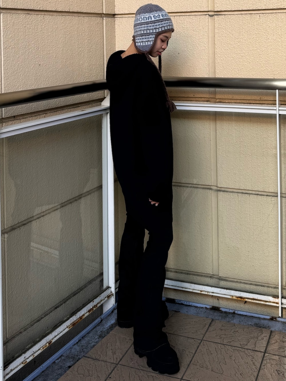 ブラック系のニット/セーター、ブルー系のデニムパンツ、ブラック系のブーツを着用したレディースの冬コーディネートの2枚目の写真