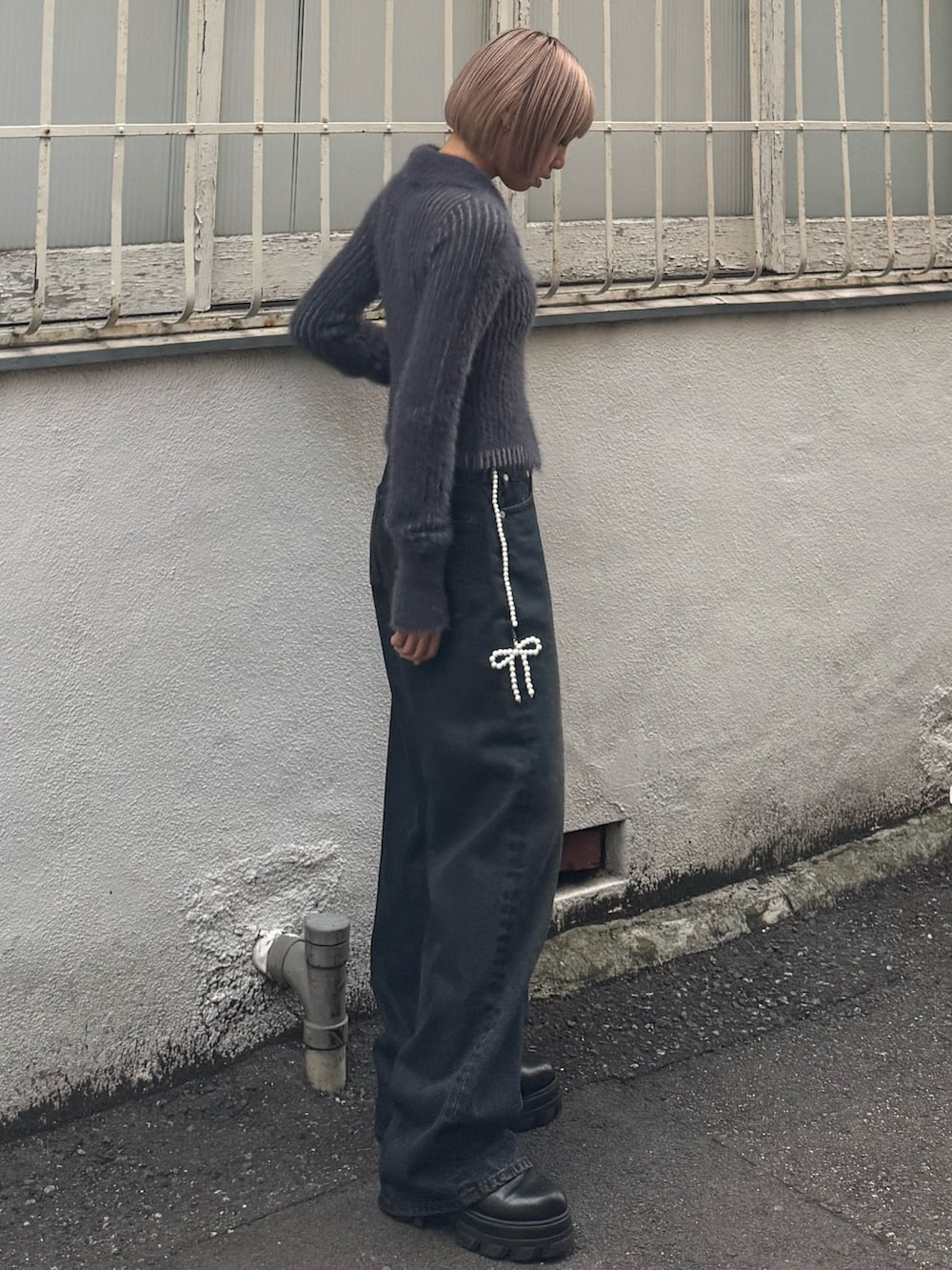 ブルー系のニット/セーター、ブルー系のデニムパンツ、ブラック系のブーツを着用したレディースの夏コーディネートの2枚目の写真