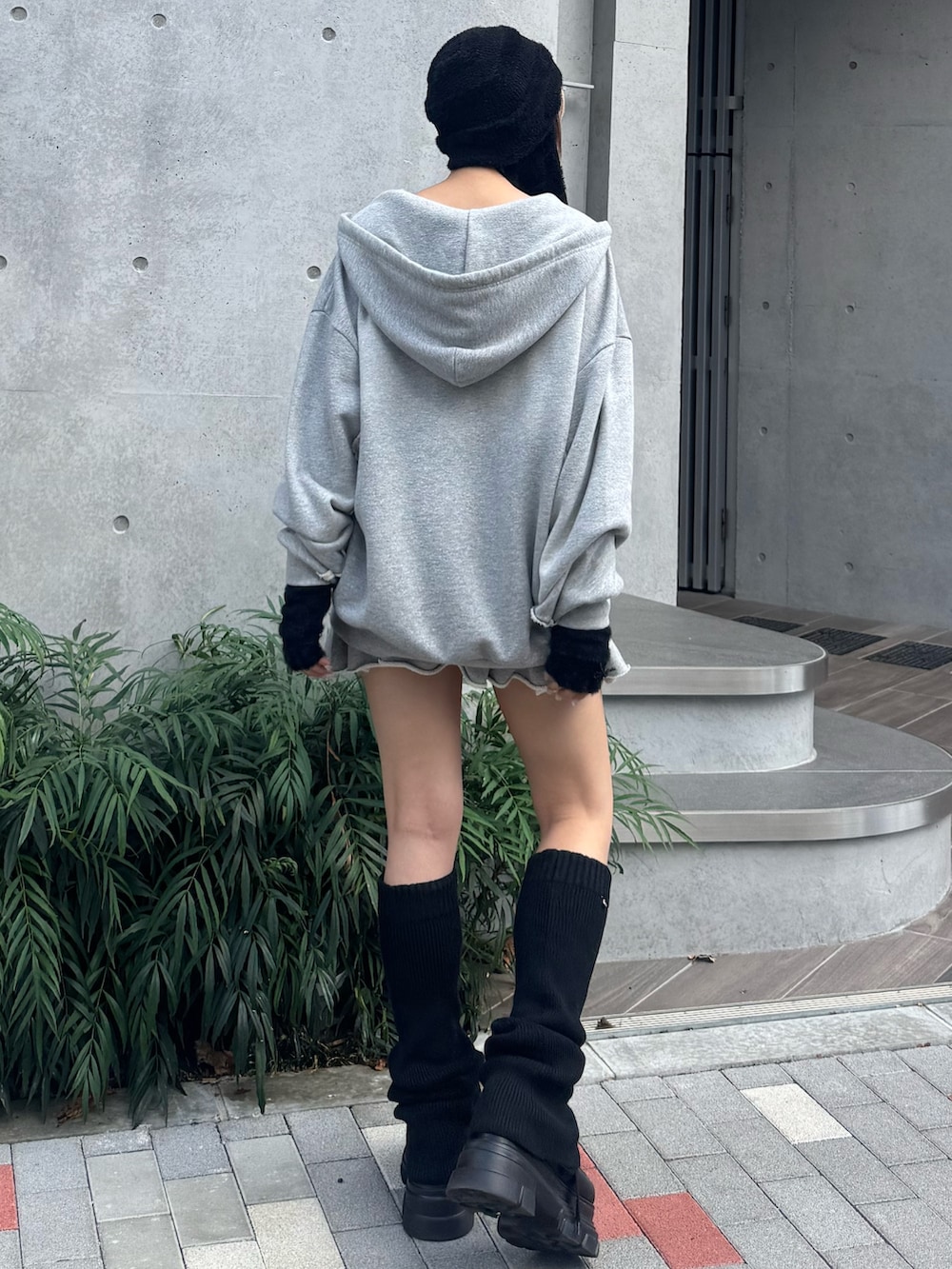 グレー系のパーカー、グレー系のスカート、ブラック系のローファーを着用したレディースの夏コーディネートの3枚目の写真