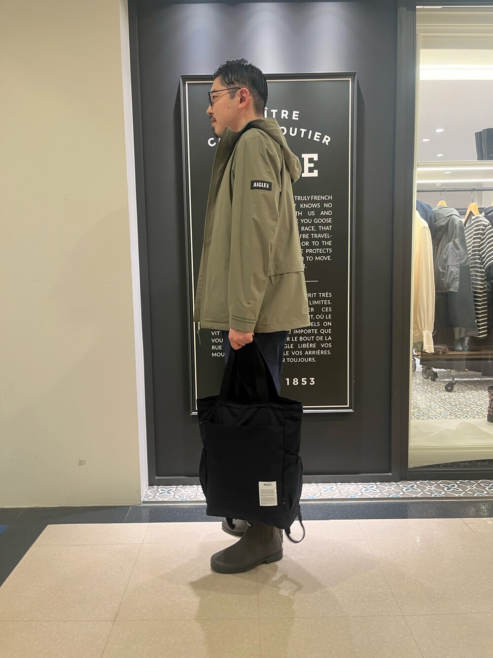 「トートバッグ、春コーデ、雨の日コーデ、大人カジュアル、レインブーツ」｜「AIGLEの透湿防水 フーデッドジャケット（マウンテンパーカー、グリーン系）」を使った、Yoshiさん（メンズ・181cm）の春コーディネートの2枚目の写真