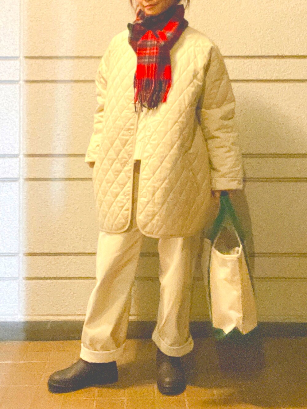 グリーン系のトートバッグ、ブラウン系のレインシューズ、ホワイト系のノーカラーコートを着用したレディースの冬コーディネートの2枚目の写真