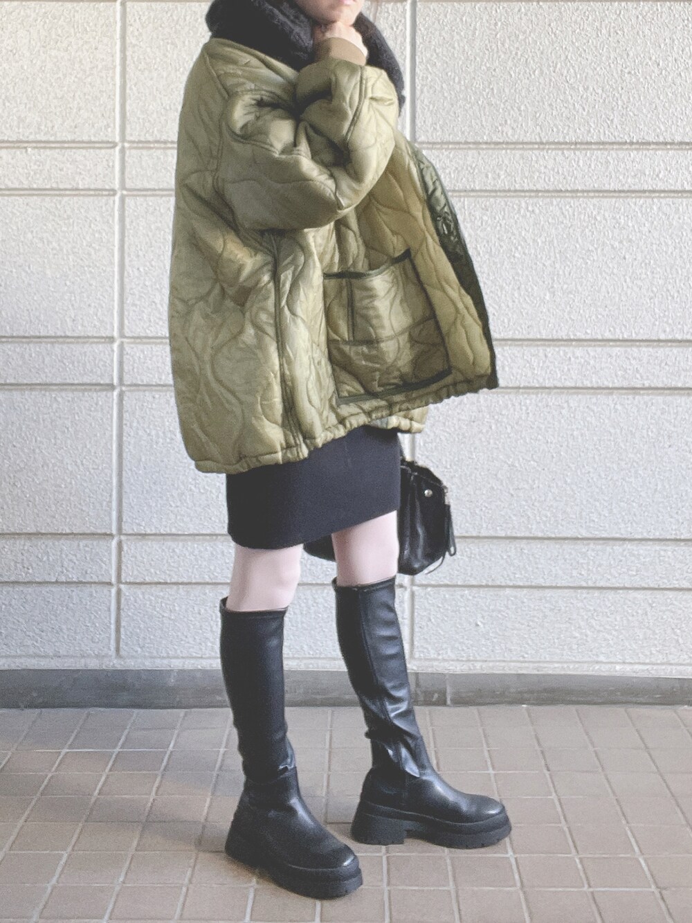 ブラック系のバッグ、ブラック系のブーツ、グリーン系のその他アウターを着用したレディースの冬コーディネートの2枚目の写真