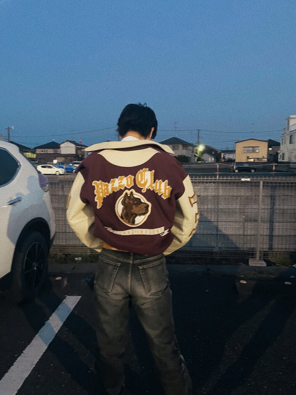 ブラック系のデニムパンツ、ホワイト系のTシャツ/カットソー、ブラウン系のスタジャンを着用したメンズの春コーディネートの2枚目の写真