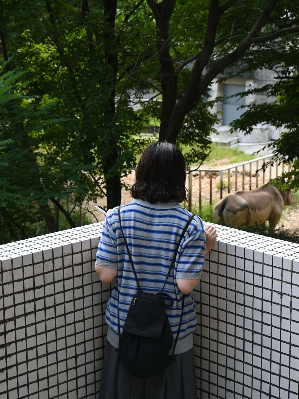 グレー系のスカート、ブルー系のスニーカー、グレー系のポロシャツを着用したレディースの夏コーディネートの2枚目の写真