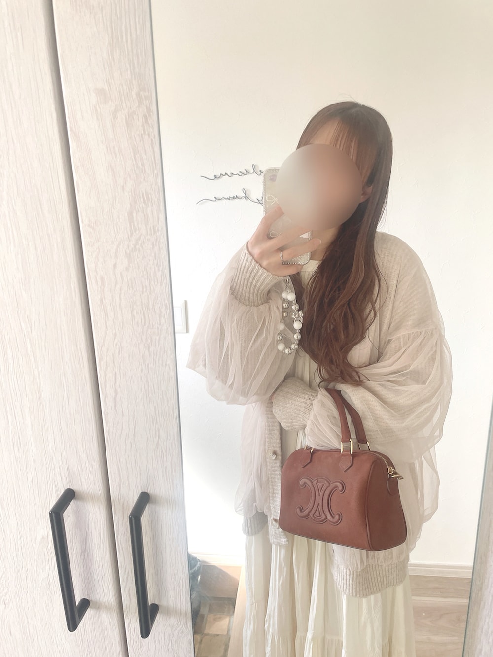 ベージュ系のカーディガン/ボレロ、ホワイト系のワンピース、ブラウン系のボストンバッグを着用したレディースの春コーディネートの2枚目の写真
