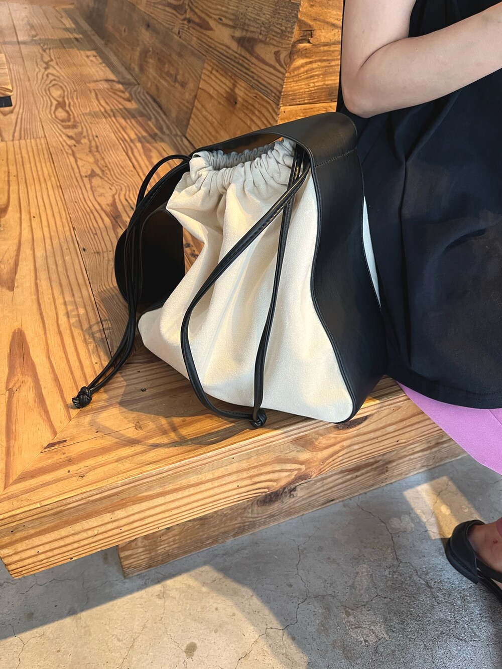 ブラック系のサンダル、ピンク系のスラックス、ブラック系のトートバッグを着用したレディースの夏コーディネートの2枚目の写真