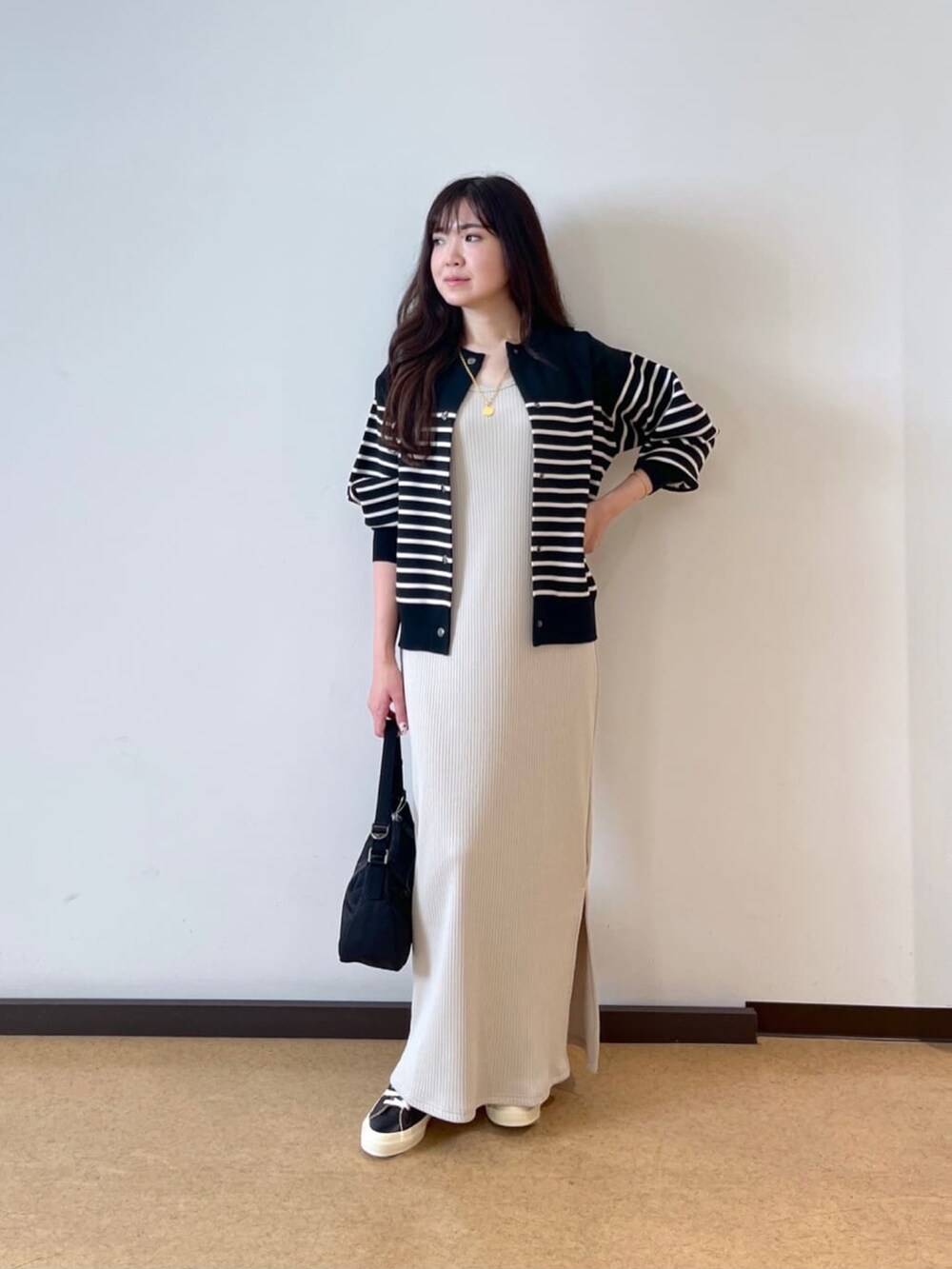 ベージュ系のワンピース、ブラック系のニット/セーターを着用したレディースの秋コーディネートの2枚目の写真