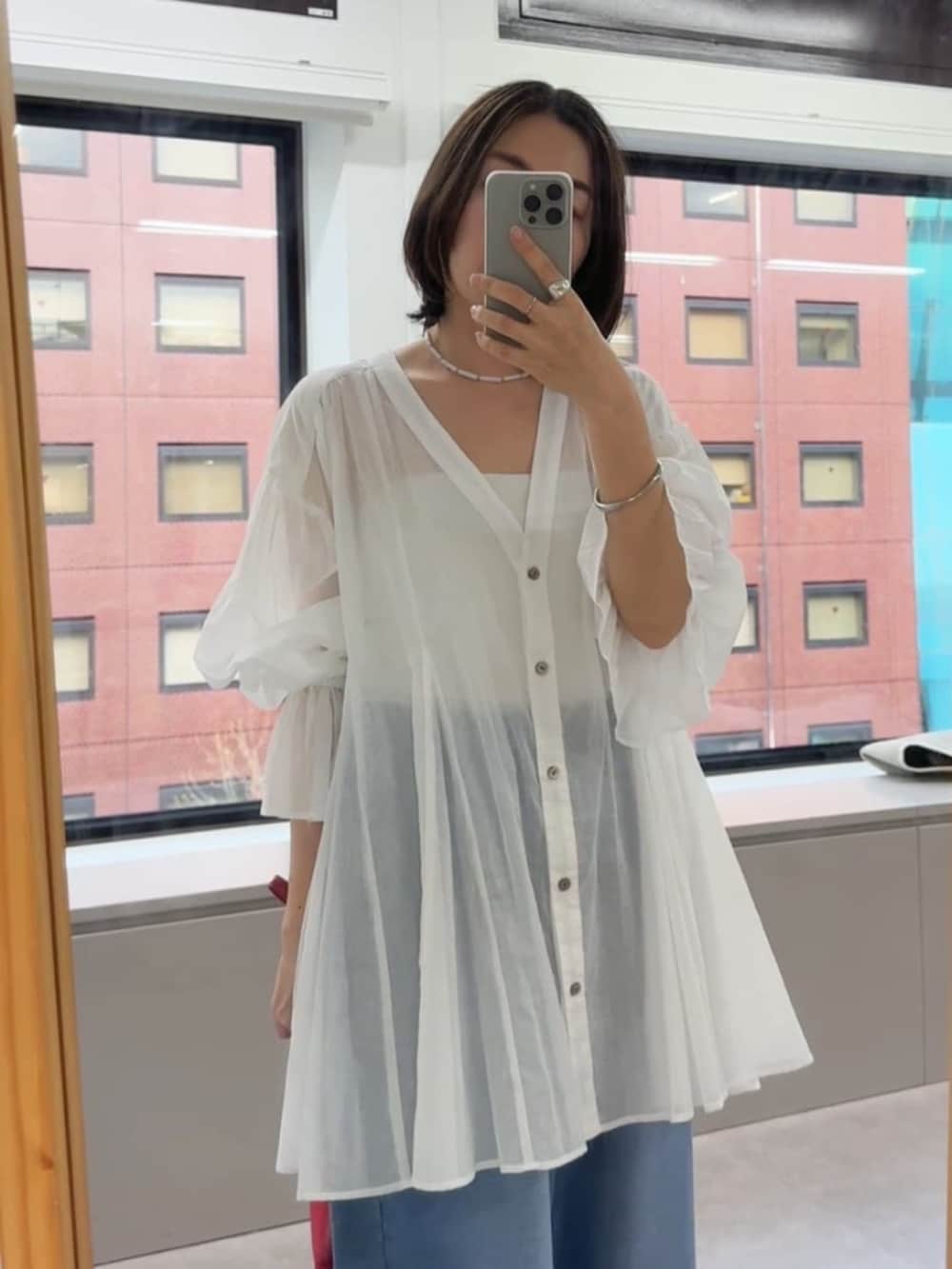 ブラック系のサンダル、ブルー系のデニムパンツ、レッド系のハンドバッグを着用したレディースの春コーディネートの4枚目の写真