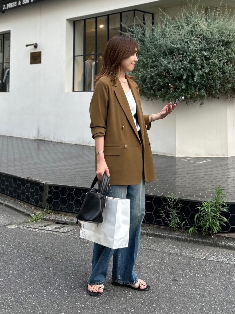 シルバー系のタンクトップ、ブラウン系のテーラードジャケット、ブルー系のデニムパンツを着用したレディースの夏コーディネートの3枚目の写真