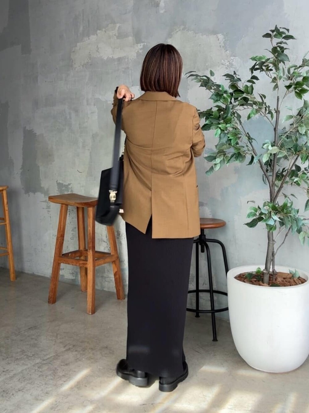 ブラック系のスウェット、ブラウン系のテーラードジャケット、ブラック系のワンピースを着用したレディースの秋コーディネートの5枚目の写真