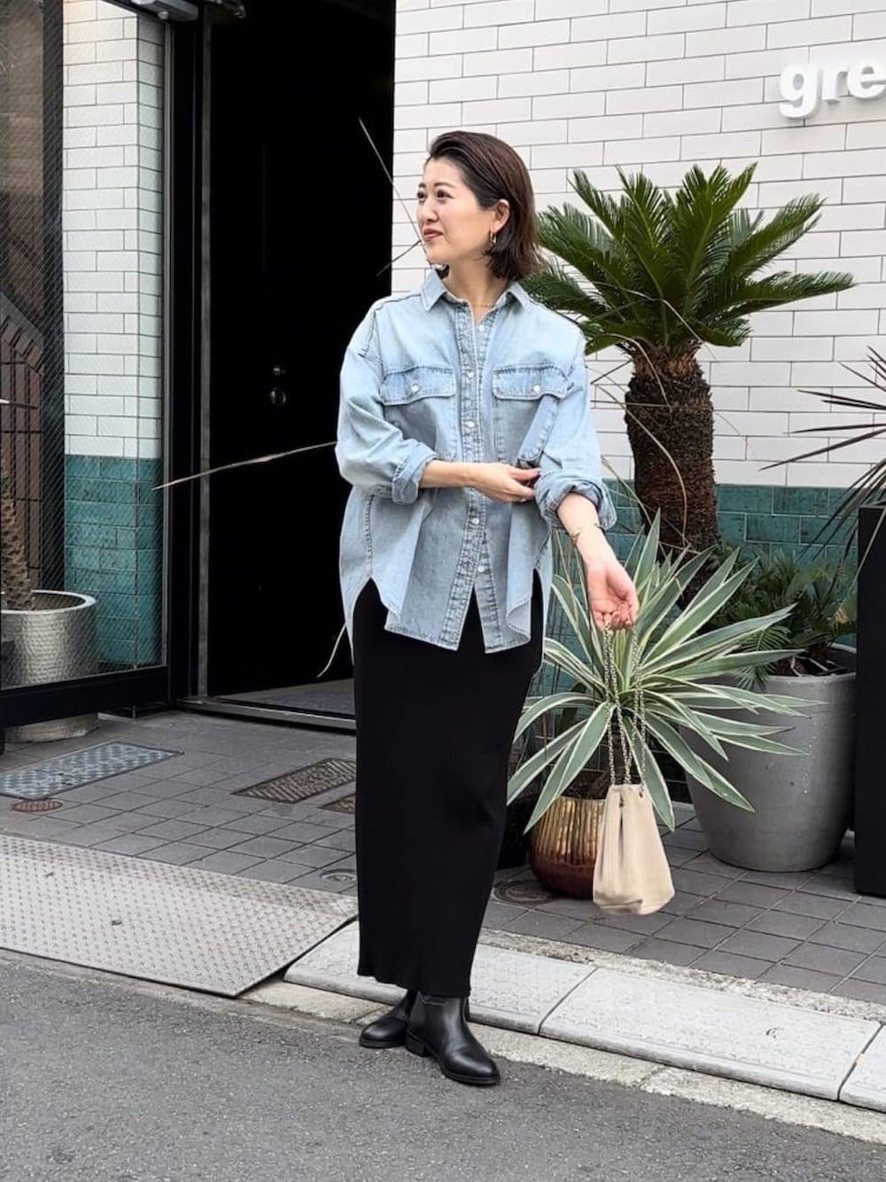 ブルー系のシャツ/ブラウス、ブラック系のスカート、ベージュ系のショルダーバッグを着用したレディースの冬コーディネートの2枚目の写真