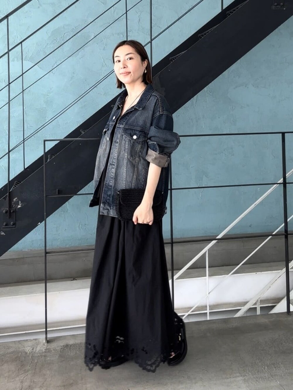 ブルー系のデニムジャケット、ブラック系のワンピース、ブラック系のサンダルを着用したレディースの夏コーディネートの2枚目の写真