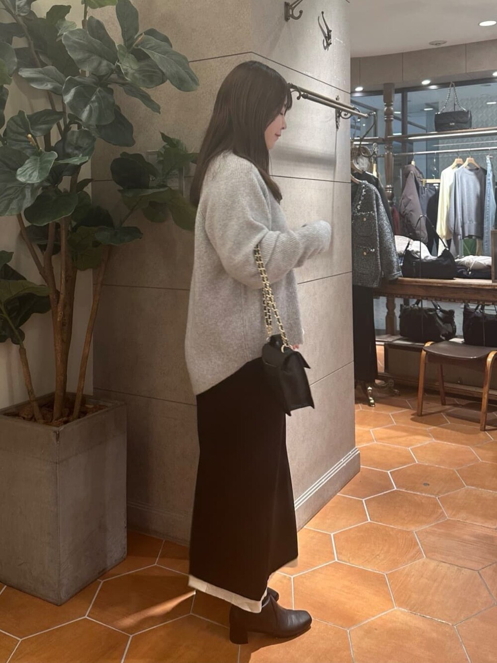 グレー系のニット/セーター、ブラック系のスカート、ブラック系のハンドバッグを着用したレディースの冬コーディネートの3枚目の写真
