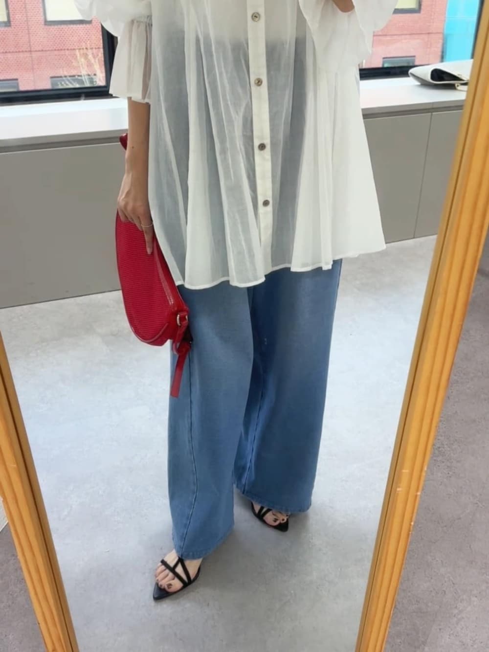 ブラック系のサンダル、ブルー系のデニムパンツ、レッド系のハンドバッグを着用したレディースの春コーディネートの5枚目の写真