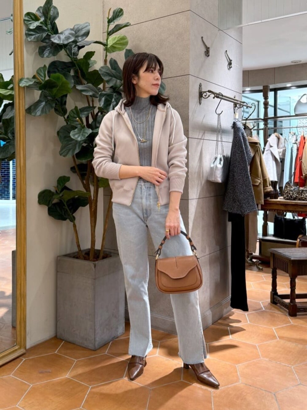 グレー系のニット/セーター、ホワイト系のダウンジャケット/コート、ブルー系のデニムパンツを着用したレディースの秋コーディネートの4枚目の写真