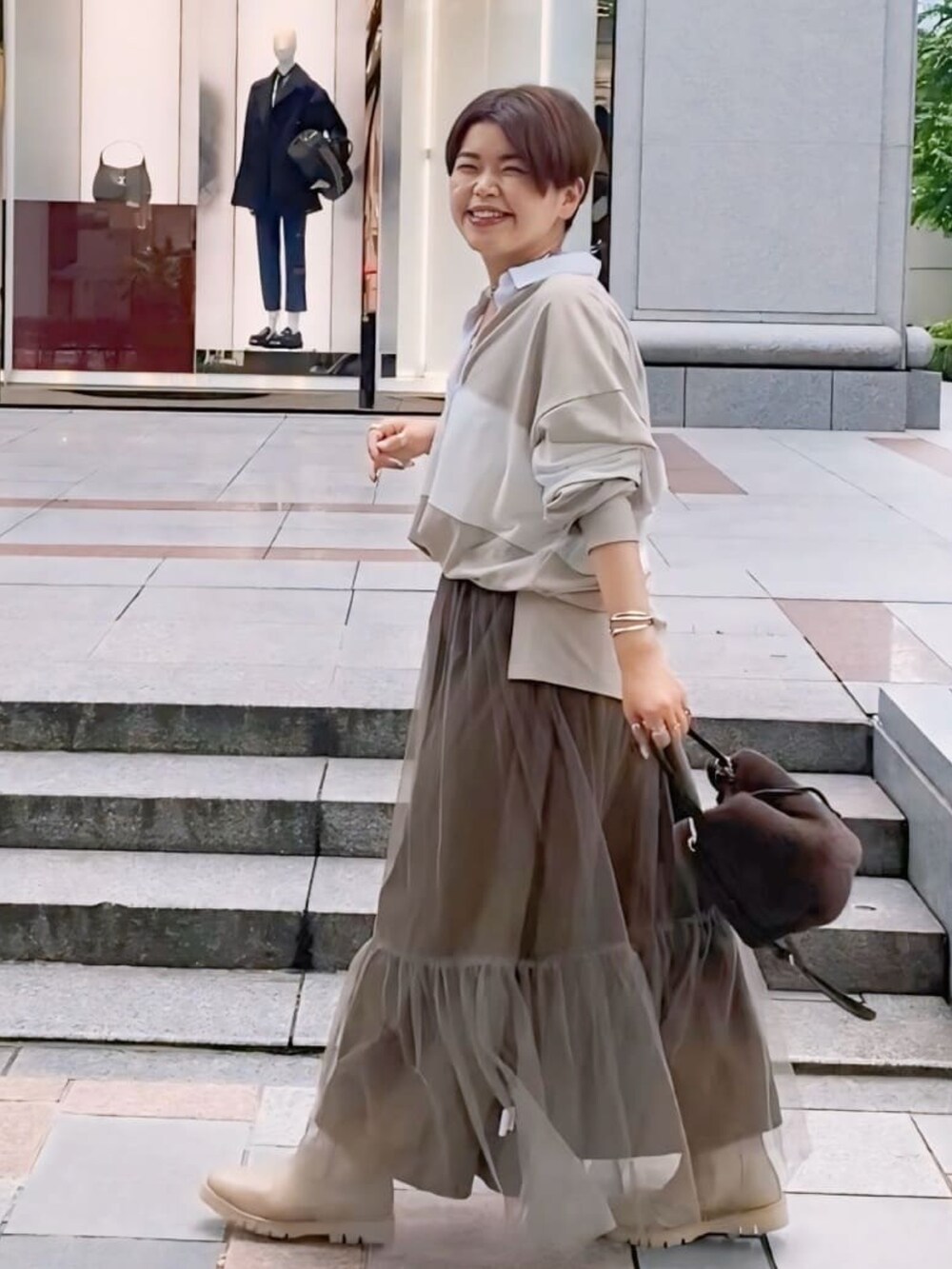 ベージュ系のTシャツ/カットソー、ブラウン系のスカート、ベージュ系のブーツを着用したレディースの夏コーディネートの2枚目の写真