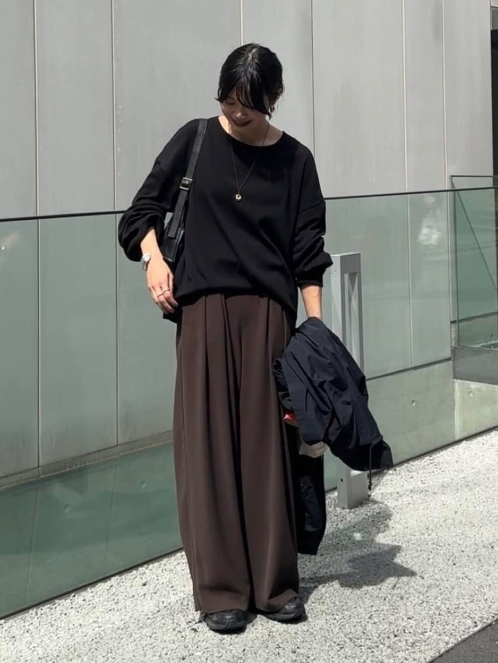 ブラック系のTシャツ/カットソー、ブラウン系のスラックスを着用したレディースの秋コーディネートの2枚目の写真