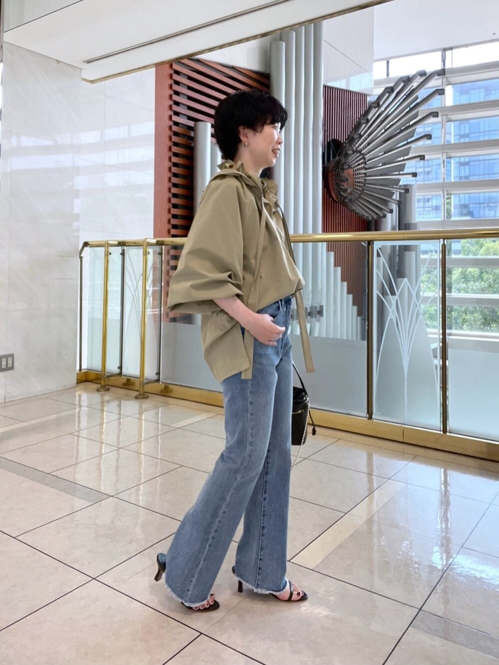 グリーン系のシャツ/ブラウス、ブラック系のハンドバッグ、ブルー系のデニムパンツを着用したレディースの夏コーディネートの2枚目の写真