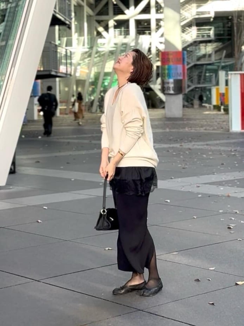 ブラック系のスカート、ブラック系のハンドバッグ、ブラック系のキャミソールを着用したレディースの冬コーディネートの7枚目の写真