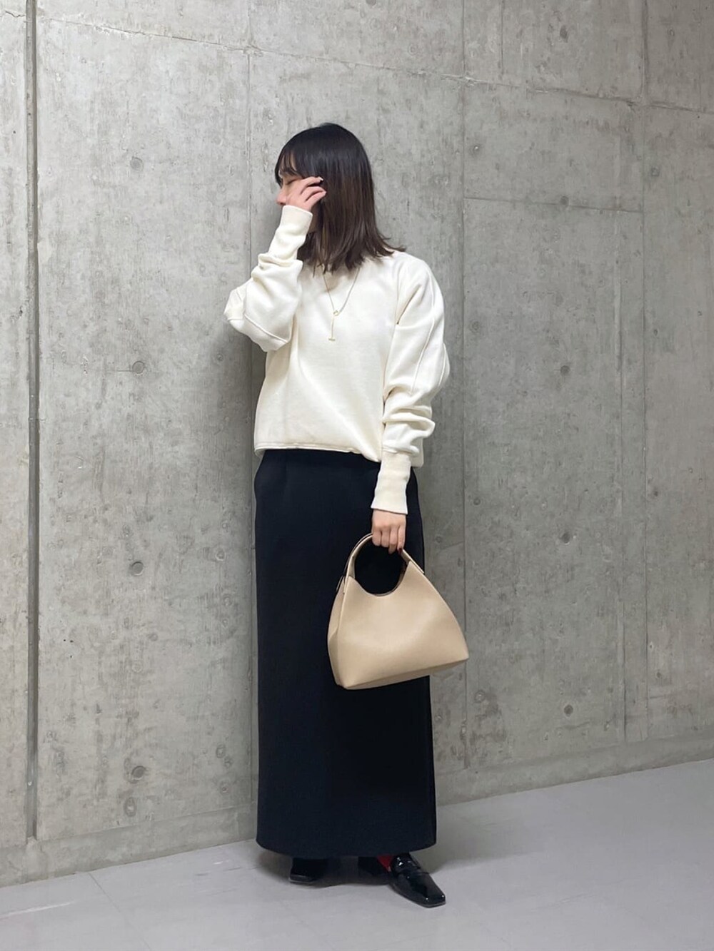 ホワイト系のニット/セーター、ベージュ系のトートバッグ、グリーン系のスカートを着用したレディースの冬コーディネートの2枚目の写真