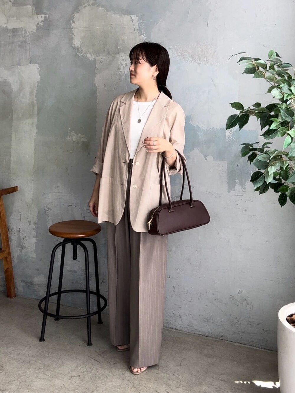 ベージュ系のテーラードジャケット、ブラウン系のショルダーバッグ、ベージュ系のスラックスを着用したレディースの夏コーディネートの3枚目の写真