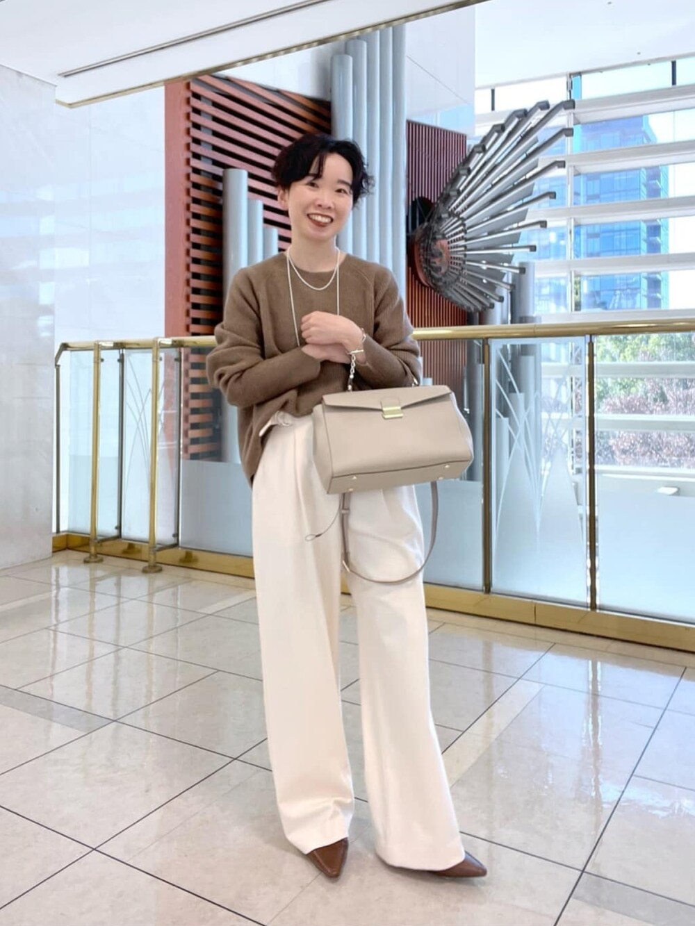 イエロー系のニット/セーター、ホワイト系のその他パンツ、ブラウン系のローファーを着用したレディースの冬コーディネートの2枚目の写真