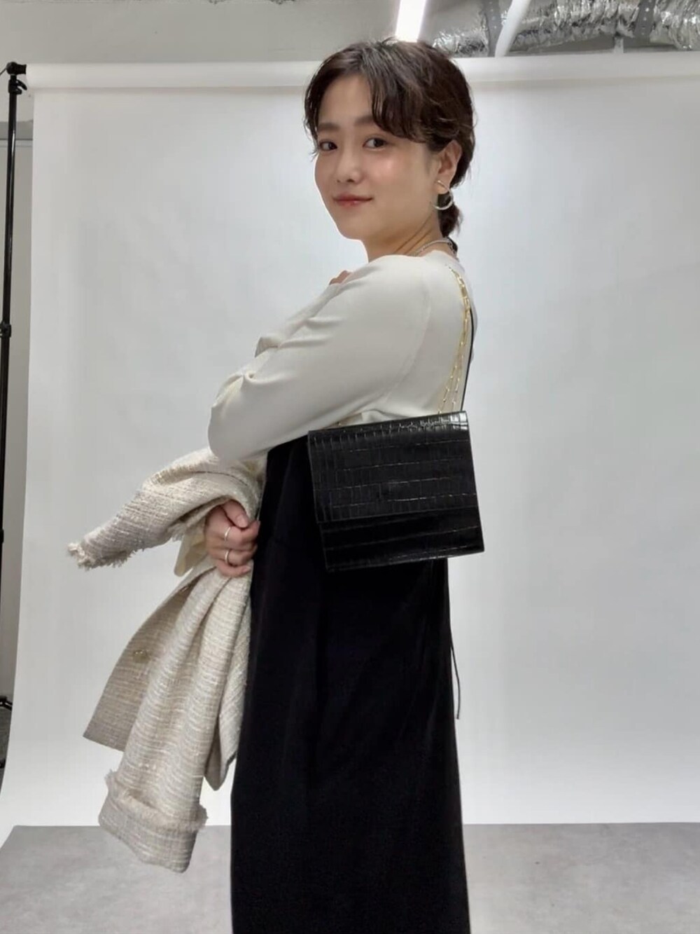 ブラック系のワンピース、シルバー系のパンプス、ブラック系のショルダーバッグを着用したレディースの冬コーディネートの3枚目の写真