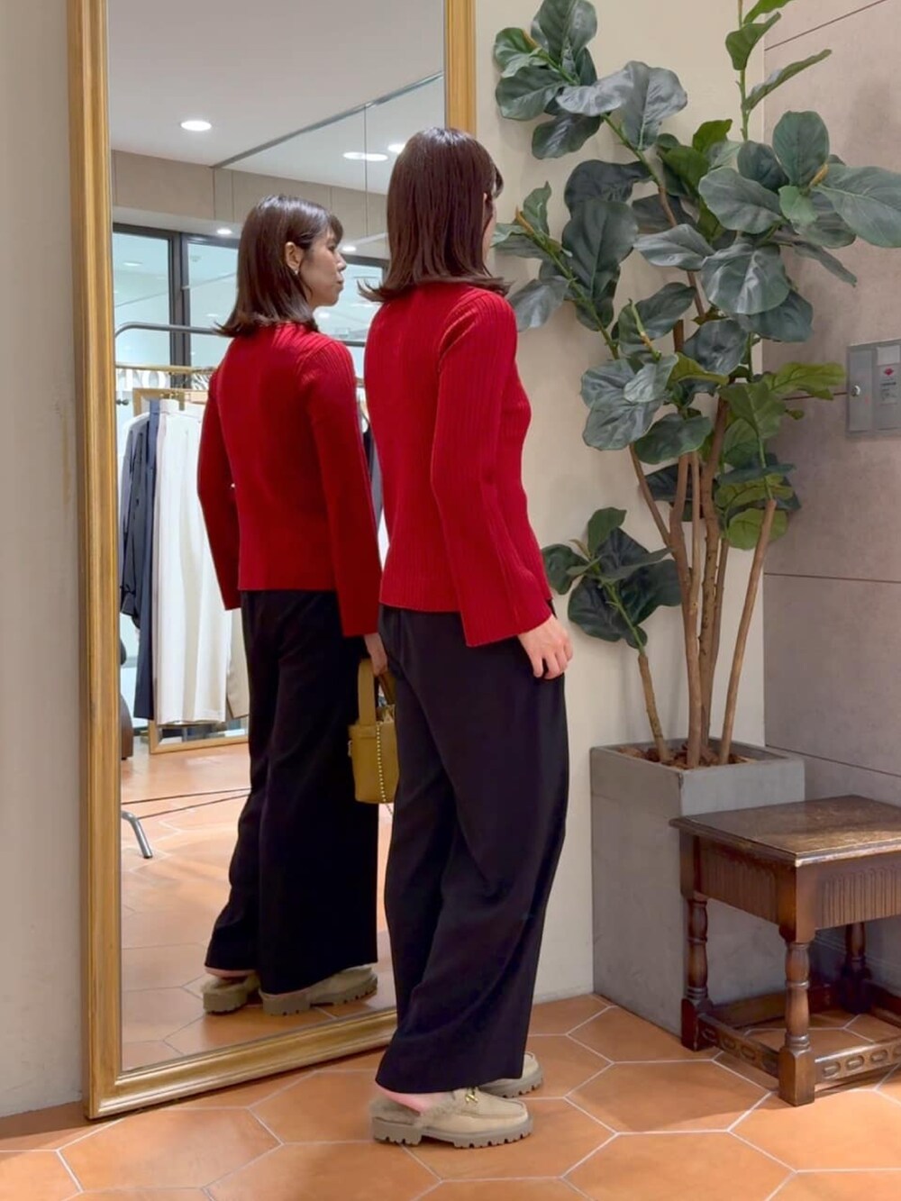 レッド系のカーディガン/ボレロ、ブラック系のスラックス、イエロー系のハンドバッグを着用したレディースの秋コーディネートの2枚目の写真