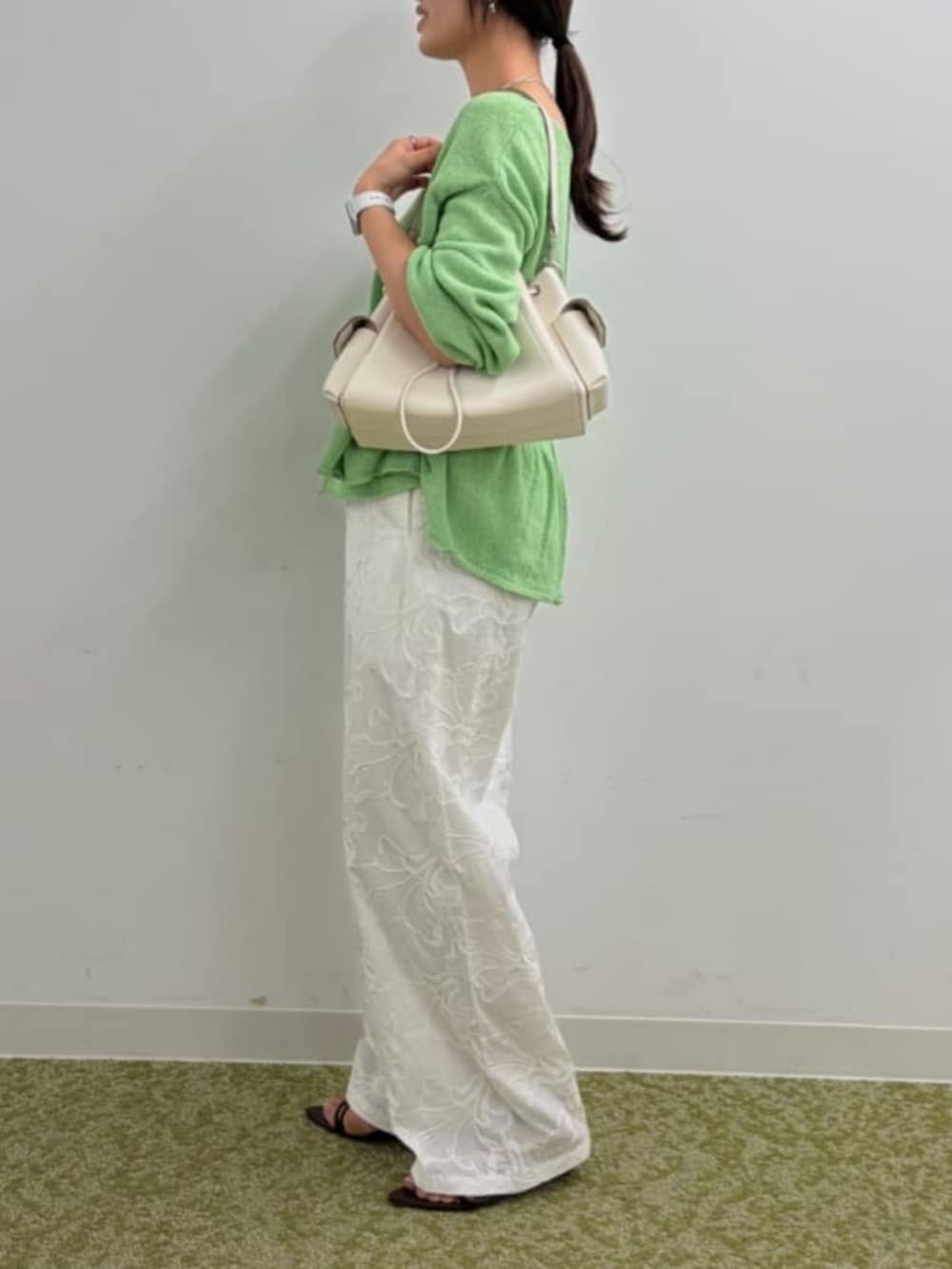 ホワイト系のショルダーバッグ、ブラウン系のサンダル、グリーン系のニット/セーターを着用したレディースの春コーディネートの2枚目の写真