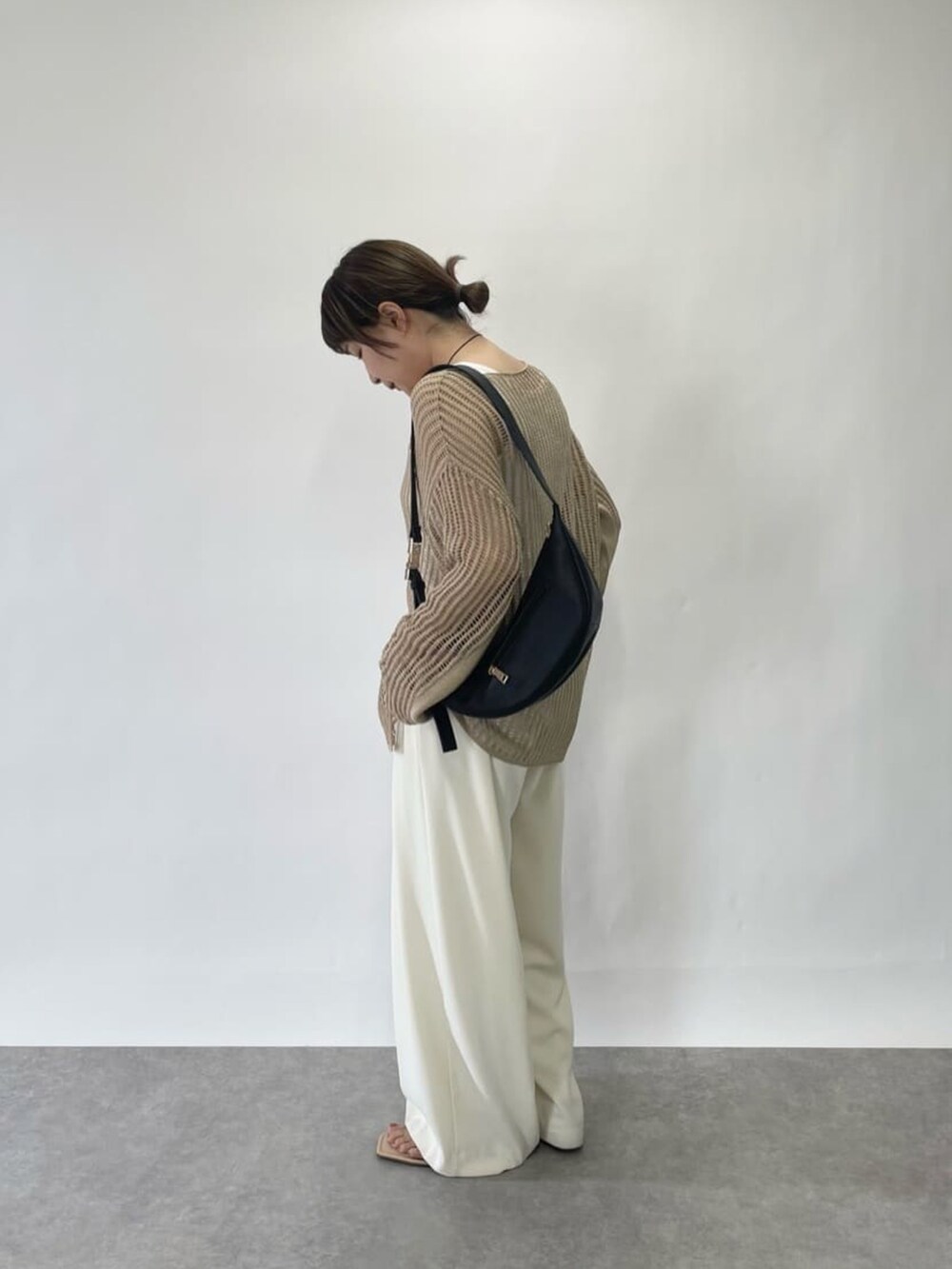 ホワイト系のニット/セーター、ホワイト系のスラックス、ブルー系のサンダルを着用したレディースの春コーディネートの3枚目の写真