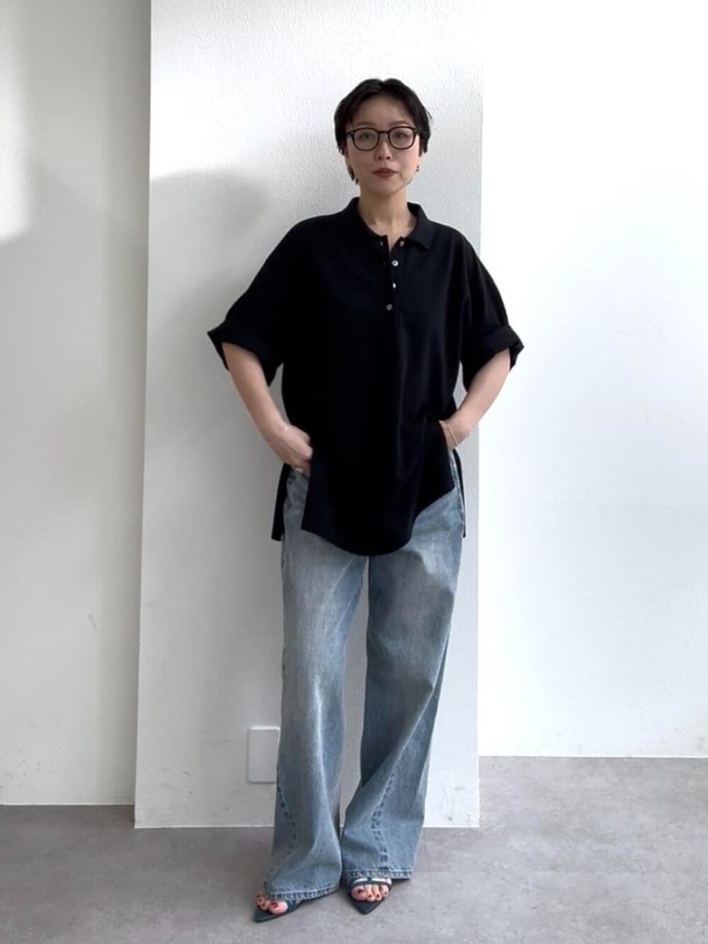 ブルー系のデニムパンツ、ブルー系のサンダル、ブラック系のポロシャツを着用したレディースの春コーディネートの2枚目の写真