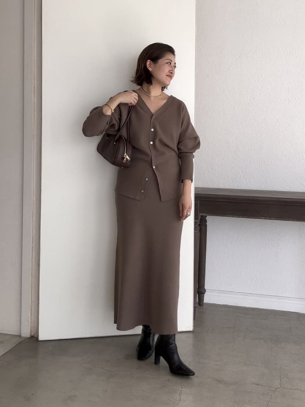 ブラウン系のカーディガン/ボレロ、ブラウン系のスカート、ブラック系のショルダーバッグを着用したレディースの秋コーディネートの3枚目の写真