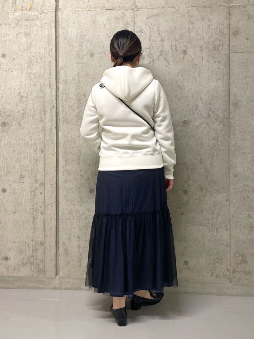 ホワイト系のパーカー、ブラック系のスカート、ブラック系のローファーを着用したレディースの春コーディネートの4枚目の写真