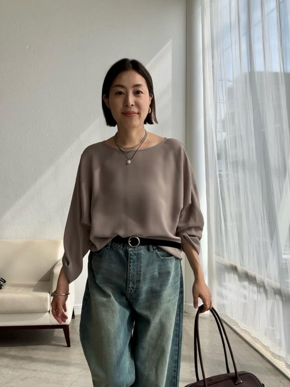 ブルー系のデニムパンツ、ブラウン系のショルダーバッグ、ブラウン系のローファーを着用したレディースの夏コーディネートの4枚目の写真