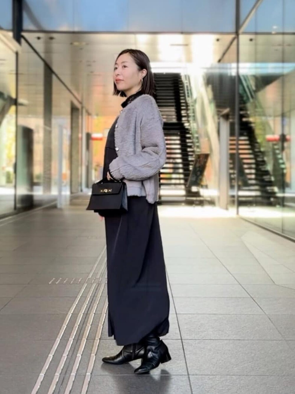 ホワイト系のTシャツ/カットソー、グレー系のカーディガン/ボレロ、ブラック系のワンピースを着用したレディースの冬コーディネートの2枚目の写真