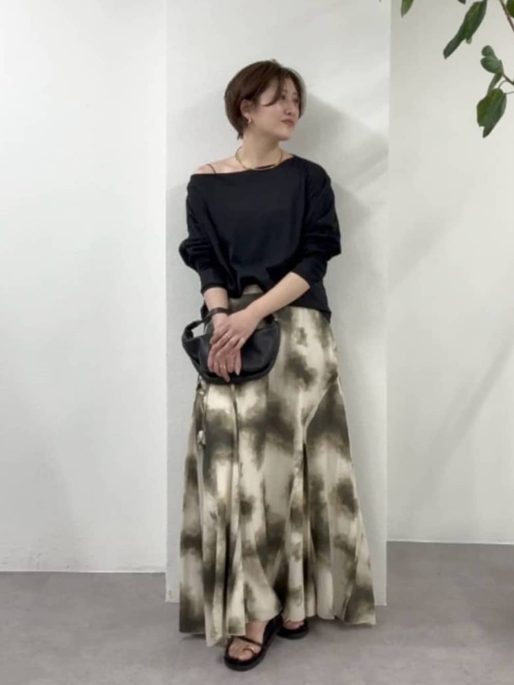 ブラック系のショルダーバッグ、ベージュ系のスカート、ブラック系のサンダルを着用したレディースの春コーディネートの4枚目の写真