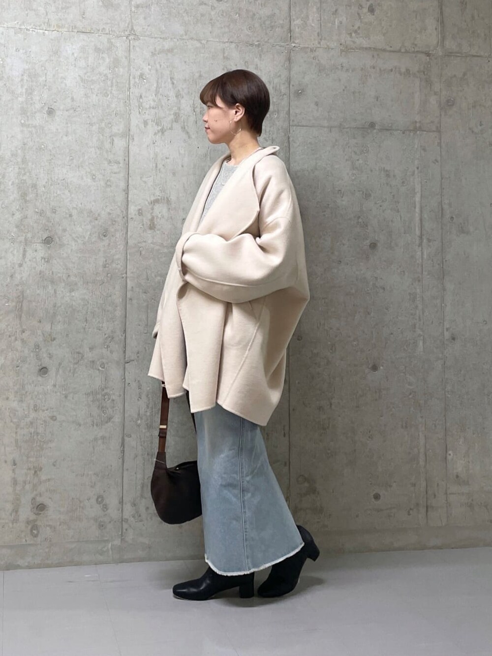 ベージュ系のその他アウター、ブルー系のデニムスカート、グレー系のニット/セーターを着用したレディースの冬コーディネートの2枚目の写真