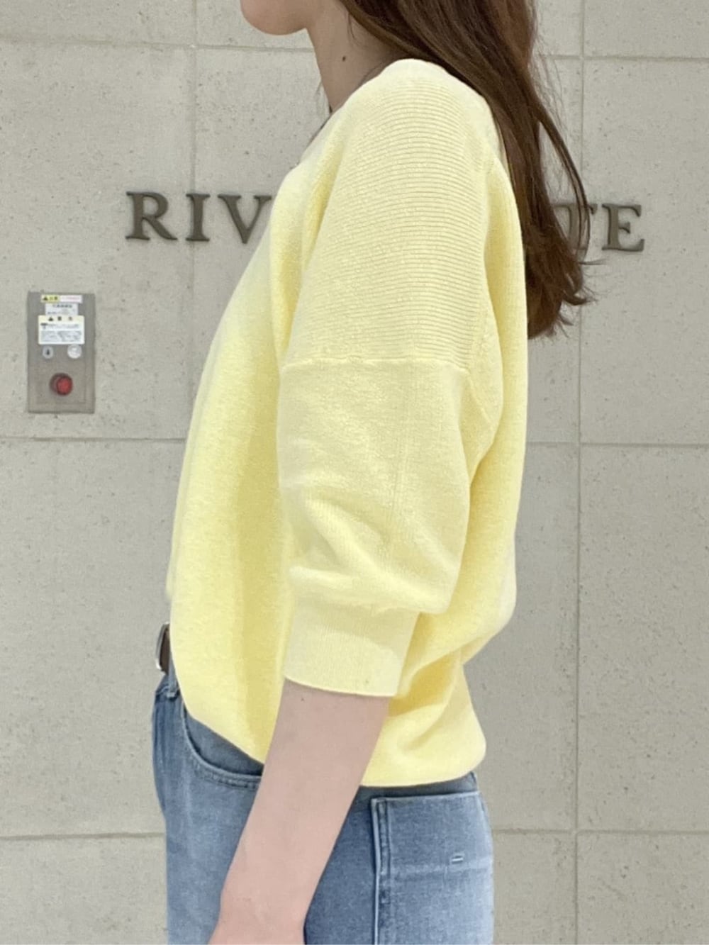 ブラウン系のボストンバッグ、イエロー系のニット/セーター、ブルー系のデニムパンツを着用したレディースの春コーディネートの5枚目の写真