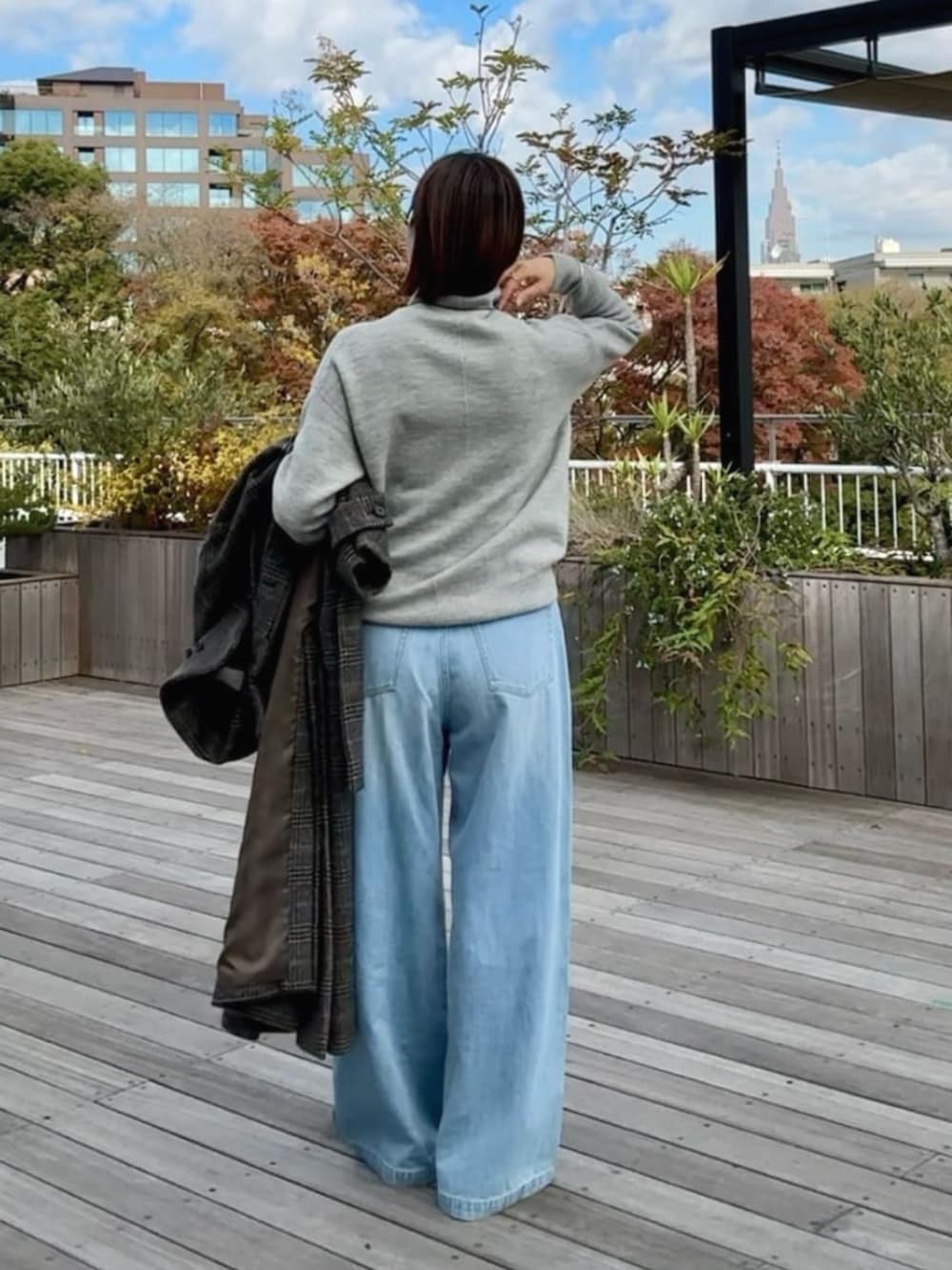 ブラック系のハンドバッグ、ブラック系のその他シューズ、ブルー系のデニムパンツを着用したレディースの冬コーディネートの2枚目の写真