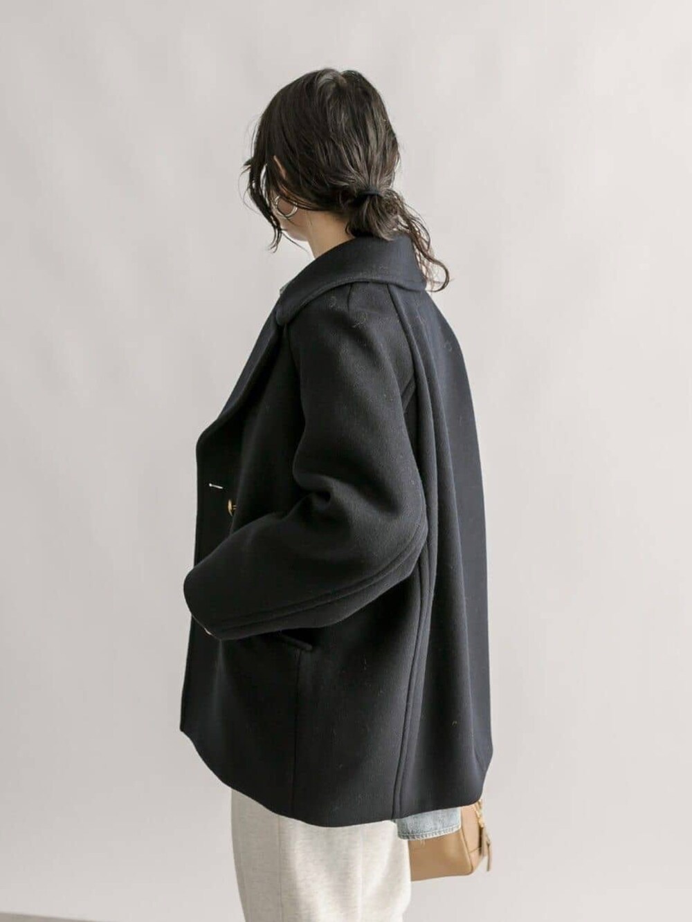 グレー系のスウェットパンツ、イエロー系のボストンバッグ、ブルー系のピーコートを着用したレディースの冬コーディネートの5枚目の写真