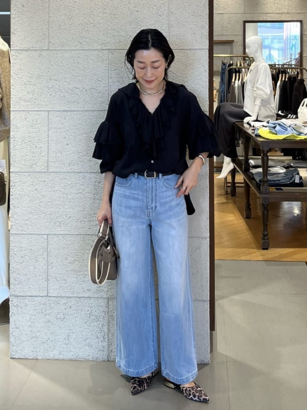 グレー系のトートバッグ、ブラック系のシャツ/ブラウス、ブルー系のデニムパンツを着用したレディースの春コーディネートの2枚目の写真