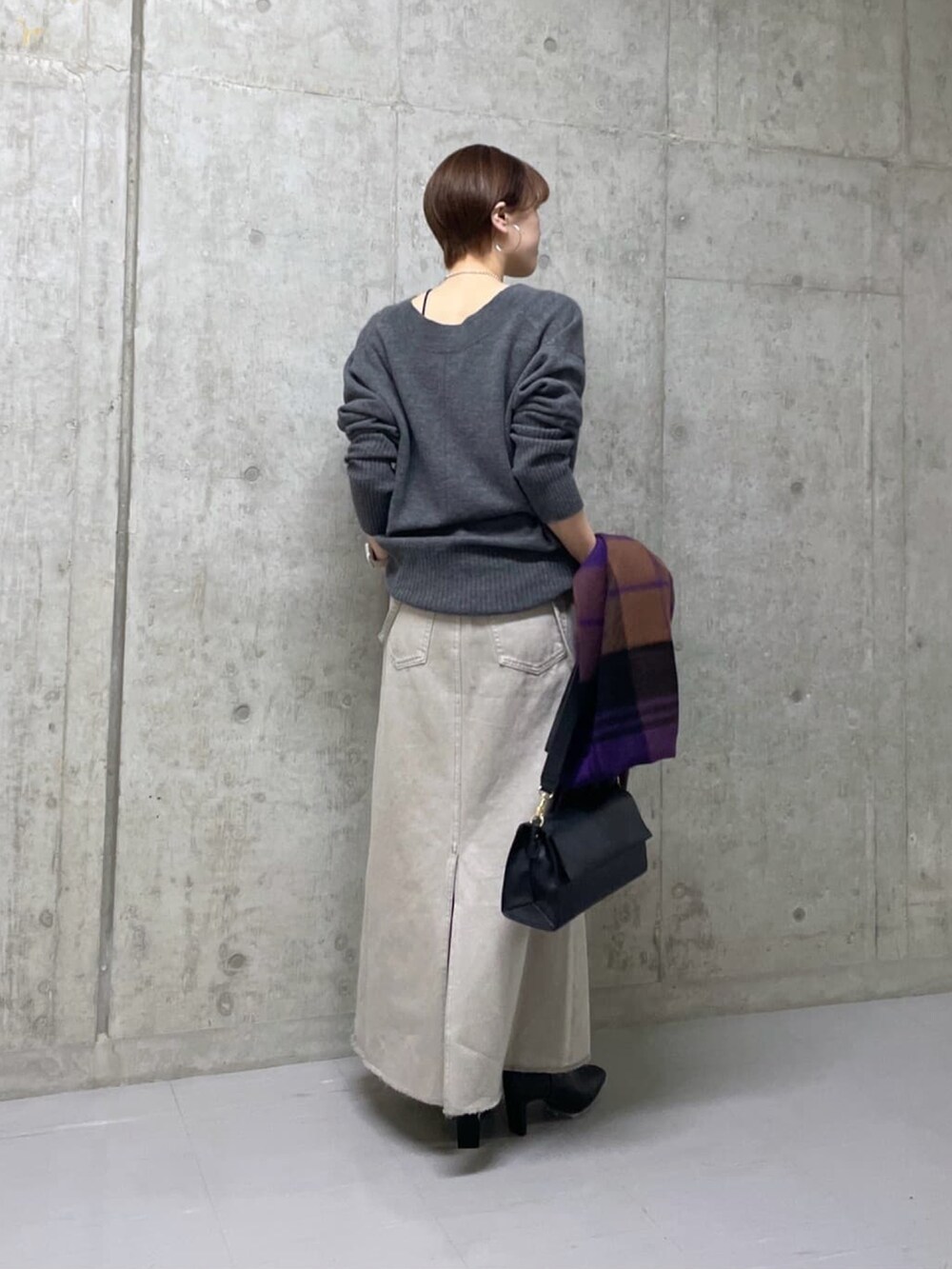 グレー系のニット/セーター、グレー系のデニムスカート、ブラック系のショルダーバッグを着用したレディースの冬コーディネートの3枚目の写真