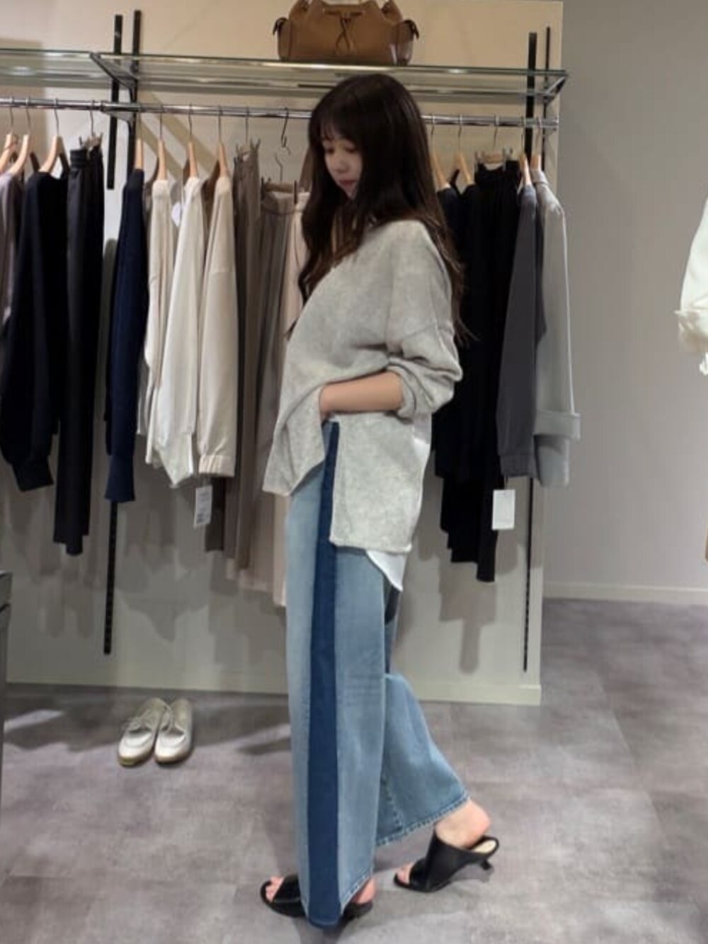 ホワイト系のシャツ/ブラウス、グレー系のニット/セーター、ブルー系のデニムパンツを着用したレディースの春コーディネートの2枚目の写真