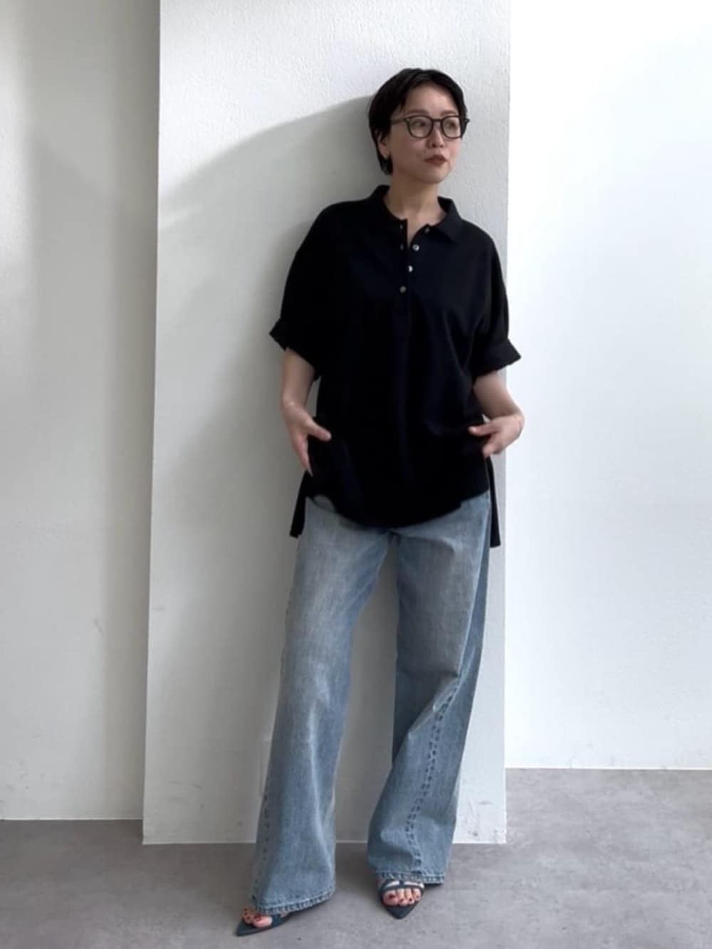ブルー系のデニムパンツ、ブルー系のサンダル、ブラック系のポロシャツを着用したレディースの春コーディネートの5枚目の写真