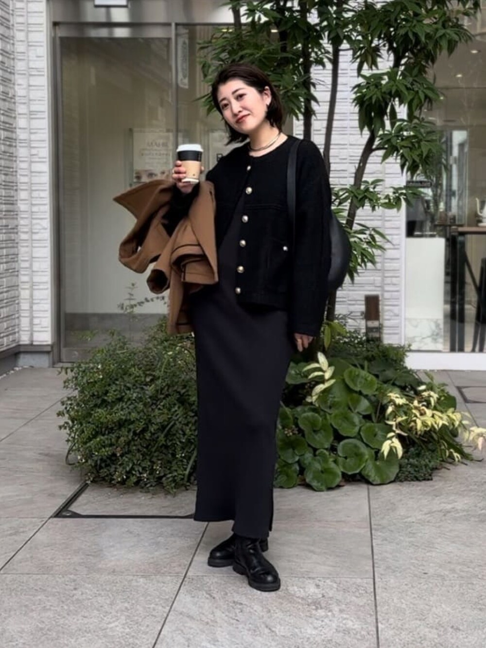 イエロー系のピーコート、ブラック系のワンピース、ブラック系のブーツを着用したレディースの冬コーディネートの4枚目の写真