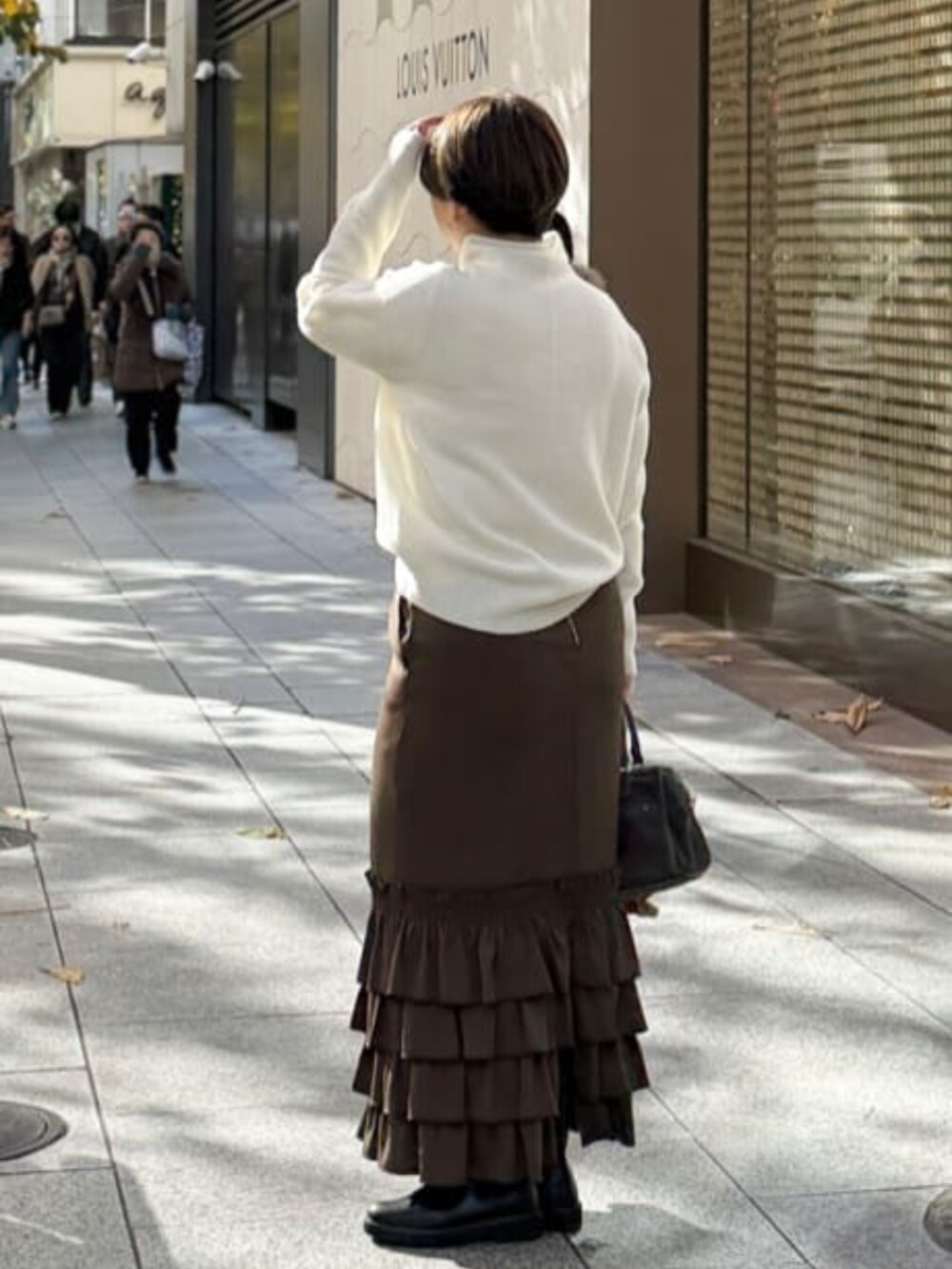 ブラウン系のスカート、ブラック系のブーツ、ホワイト系のニット/セーターを着用したレディースの冬コーディネートの3枚目の写真