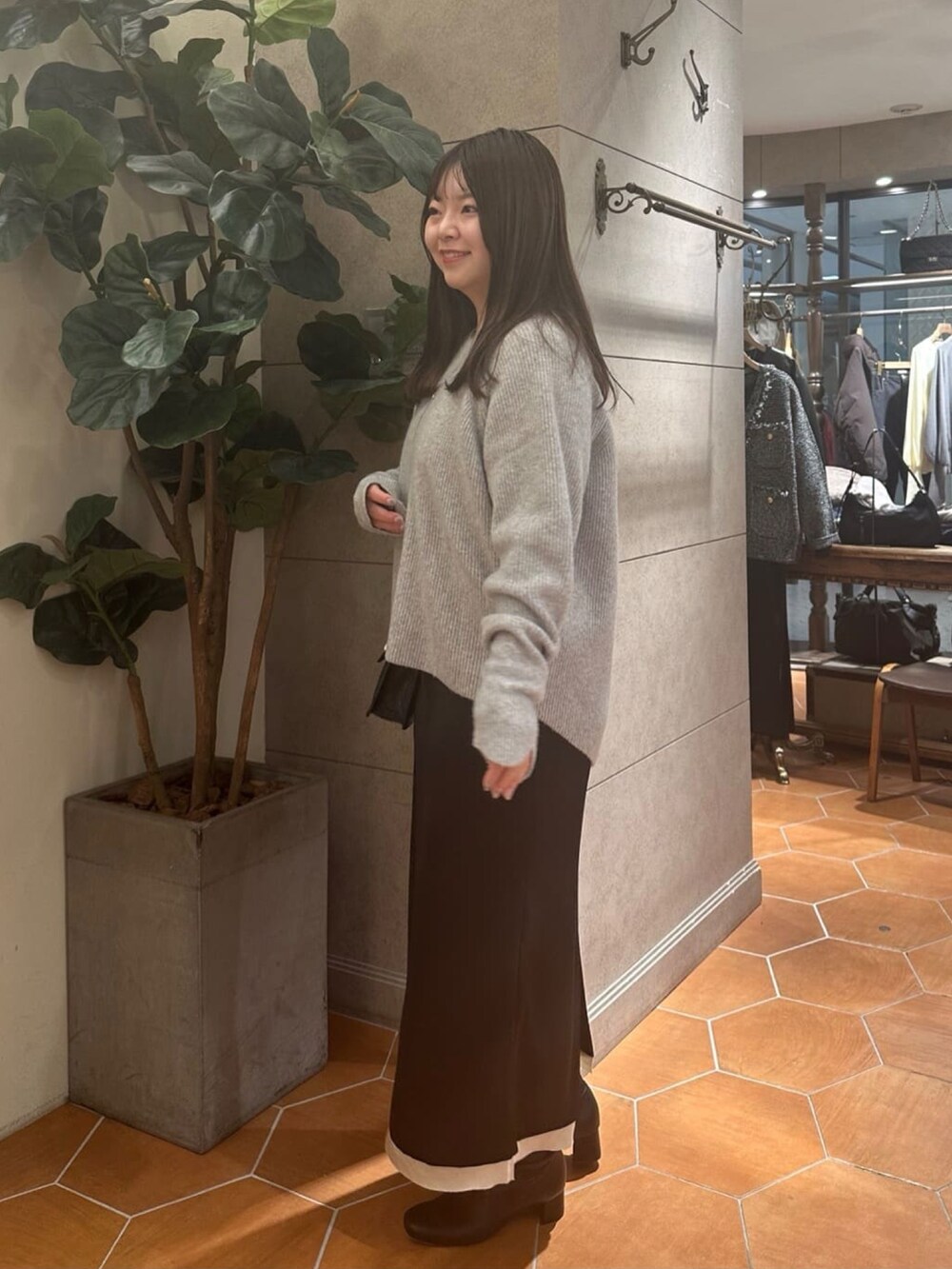 グレー系のニット/セーター、ブラック系のスカート、ブラック系のハンドバッグを着用したレディースの冬コーディネートの2枚目の写真