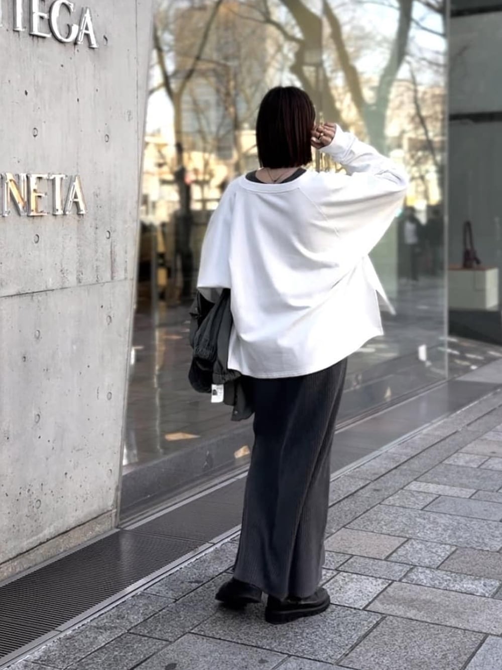 グレー系のワンピース、グリーン系のマウンテンパーカー、ブラック系のブーツを着用したレディースの冬コーディネートの3枚目の写真