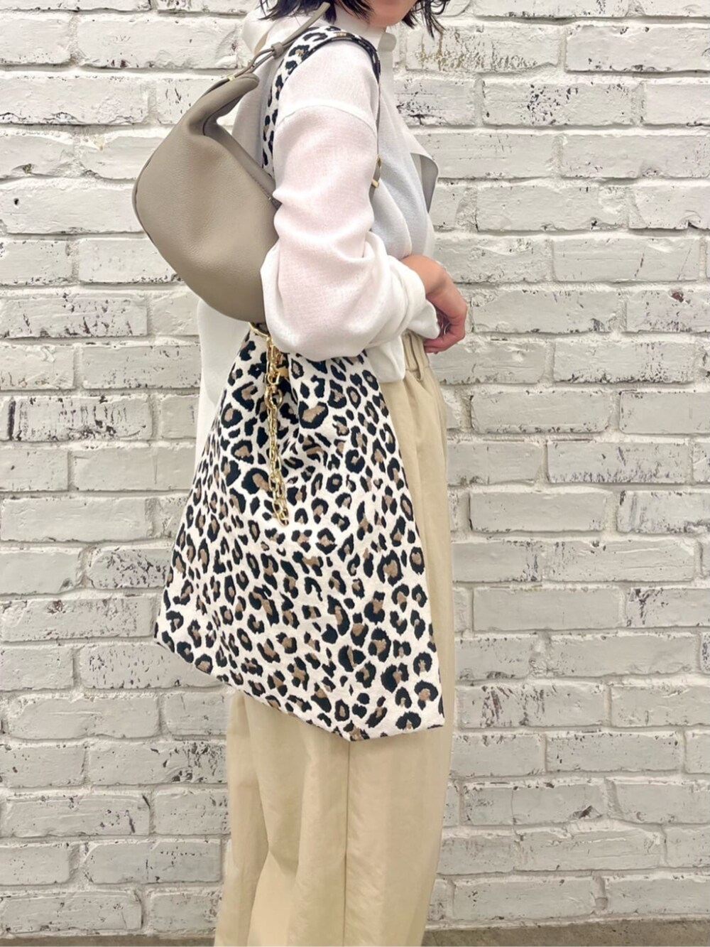 ベージュ系のショルダーバッグ、ホワイト系のシャツ/ブラウス、ベージュ系のトートバッグを着用したレディースの春コーディネートの2枚目の写真