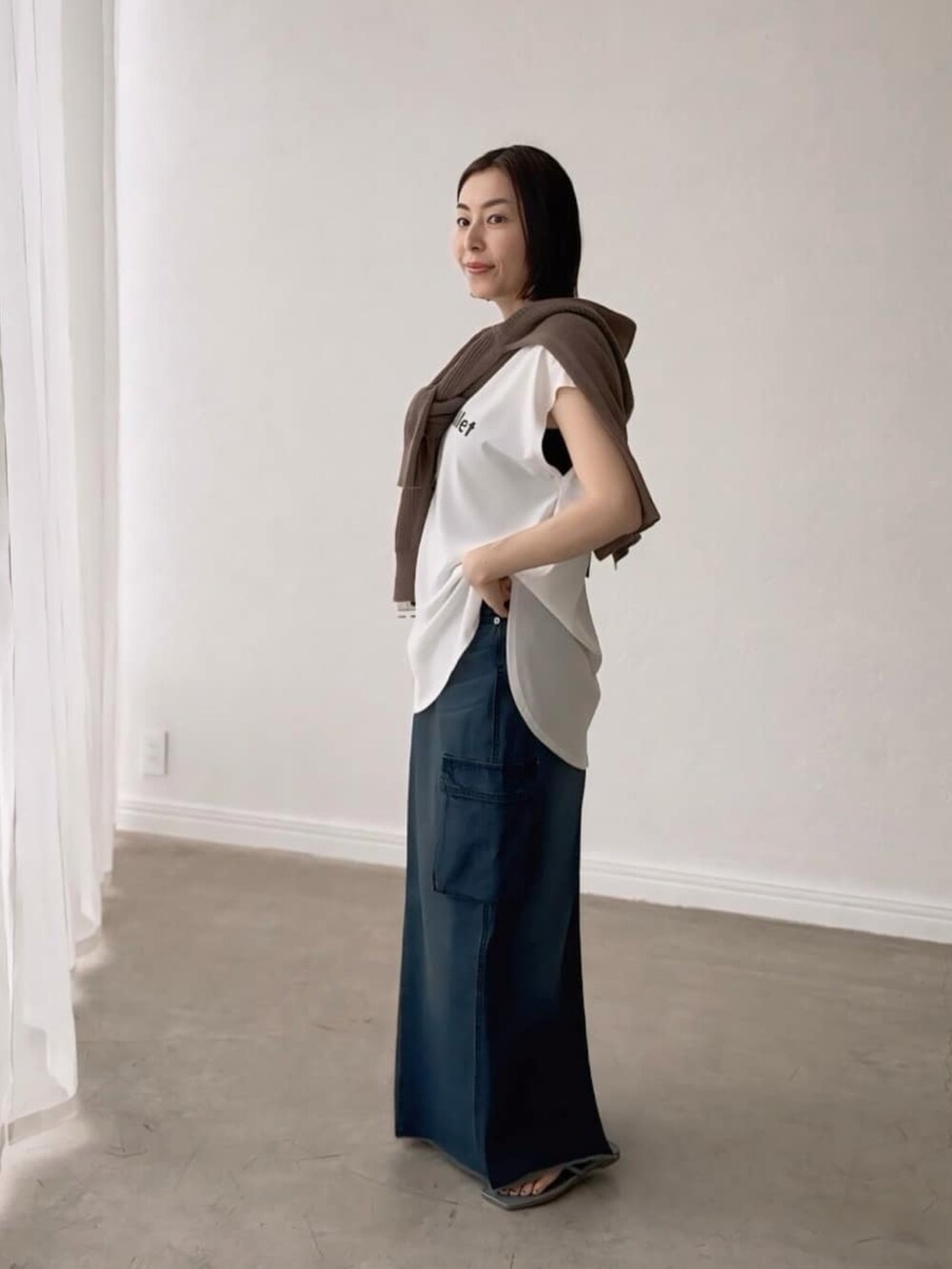 ホワイト系のシャツ/ブラウス、ブラウン系のカーディガン/ボレロ、ブルー系のデニムスカートを着用したレディースの春コーディネートの2枚目の写真